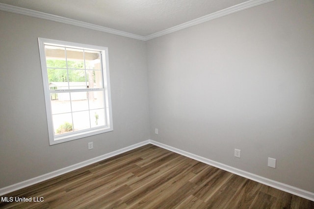 spare room featuring baseboards, ornamental molding, dark wood-style flooring, and a wealth of natural light