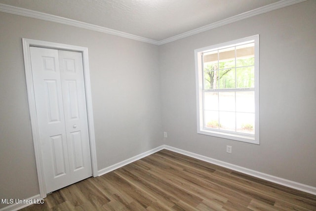 spare room featuring crown molding, baseboards, and wood finished floors