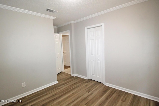 empty room featuring crown molding, baseboards, dark wood finished floors, and visible vents