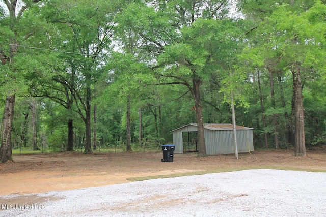 exterior space with a view of trees and gravel driveway