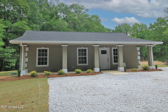 ranch-style home with a porch, roof with shingles, and stucco siding