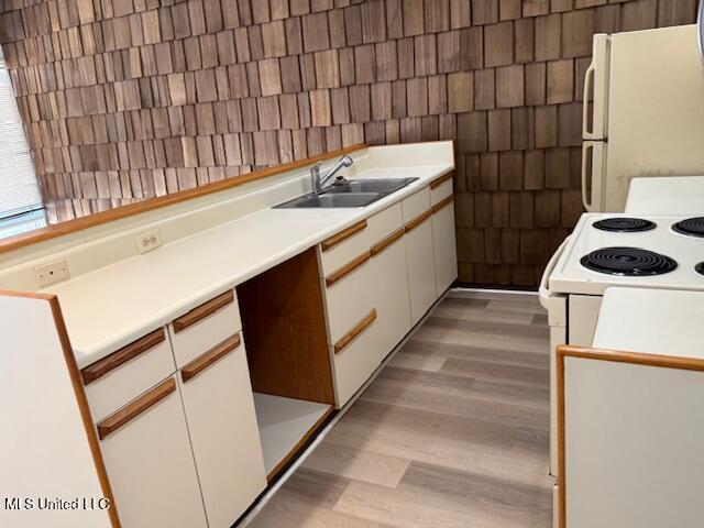 kitchen featuring white appliances, light wood-style floors, light countertops, white cabinets, and a sink
