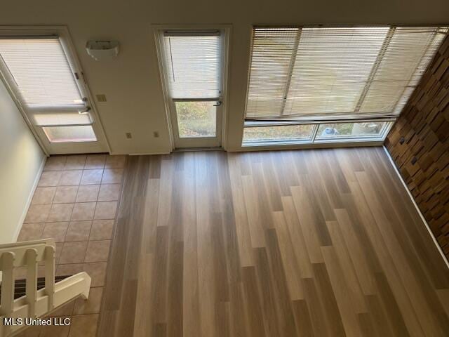 empty room with plenty of natural light, baseboards, and wood finished floors