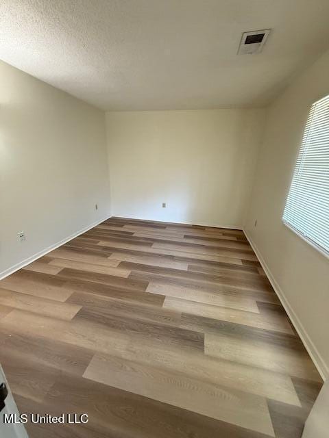 empty room featuring visible vents, baseboards, and wood finished floors
