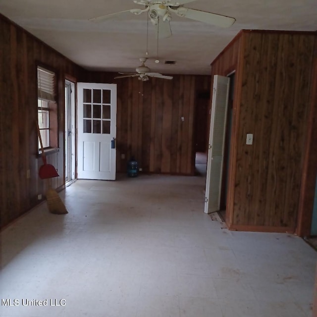 interior space with wood walls and ceiling fan