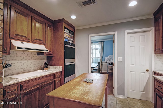 320 Woodhollow Cv, Brandon, MS 39047 - kitchen featuring under cabinet range hood, backsplash, cooktop, a center island, and light tile patterned flooring