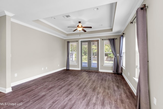 spare room featuring a tray ceiling, visible vents, dark wood-style floors, and ceiling fan