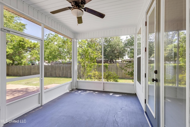 unfurnished sunroom featuring a ceiling fan and plenty of natural light
