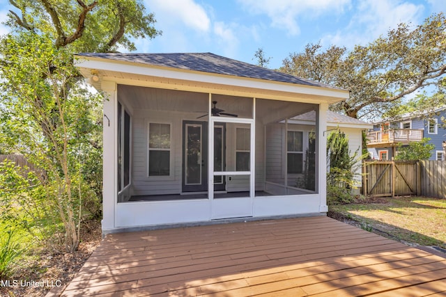 wooden terrace with a sunroom, a gate, a ceiling fan, and fence
