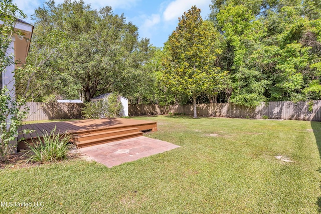 view of yard with an outdoor structure, a wooden deck, a fenced backyard, and a shed