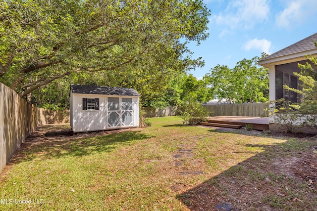 view of yard featuring an outdoor structure, a deck, a shed, and a fenced backyard