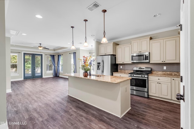 kitchen featuring visible vents, ornamental molding, cream cabinets, tasteful backsplash, and appliances with stainless steel finishes