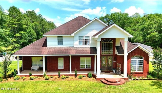 17500 Goff Farm Rd, Moss Point, MS 39562 - traditional home with covered porch, a front lawn, a shingled roof, brick siding, and french doors