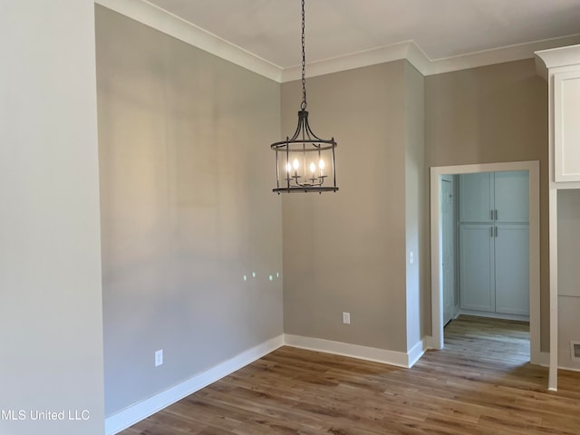 unfurnished dining area with a chandelier, ornamental molding, and hardwood / wood-style flooring