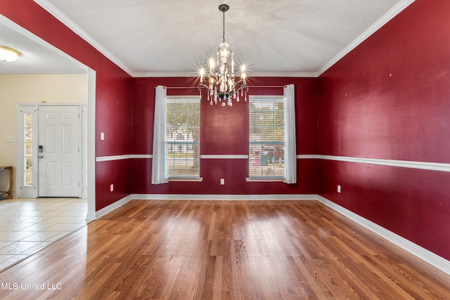 unfurnished dining area featuring crown molding, hardwood / wood-style floors, a chandelier, and a textured ceiling