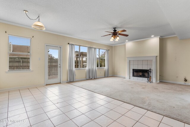 unfurnished living room with ornamental molding, a textured ceiling, light colored carpet, and a tile fireplace