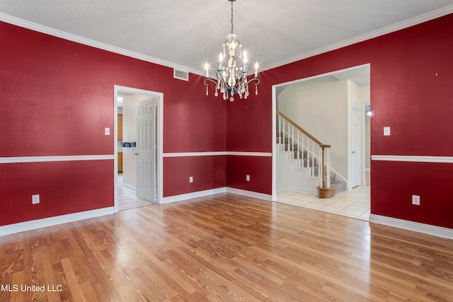 empty room with crown molding, a textured ceiling, light hardwood / wood-style flooring, and an inviting chandelier