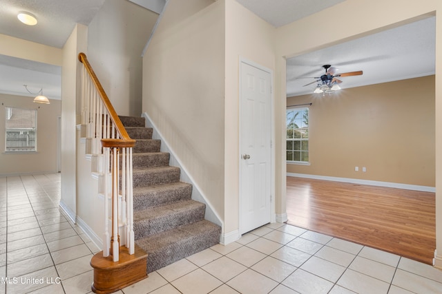 staircase with a textured ceiling, hardwood / wood-style flooring, and ceiling fan