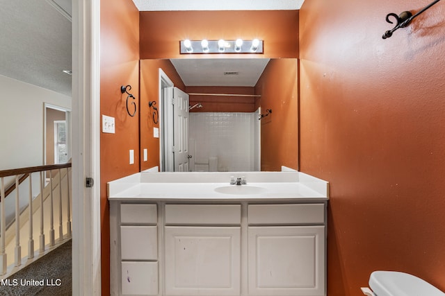 bathroom featuring vanity, toilet, and walk in shower