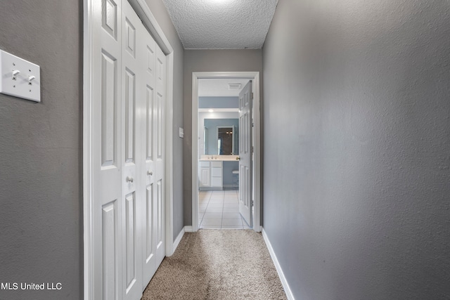 corridor with a textured ceiling and light colored carpet