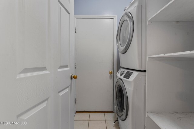 laundry area with light tile patterned flooring and stacked washer and dryer