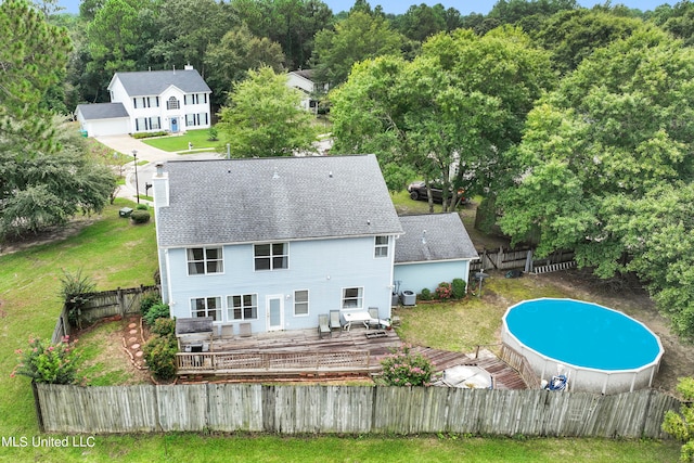 back of house with a pool side deck and a lawn