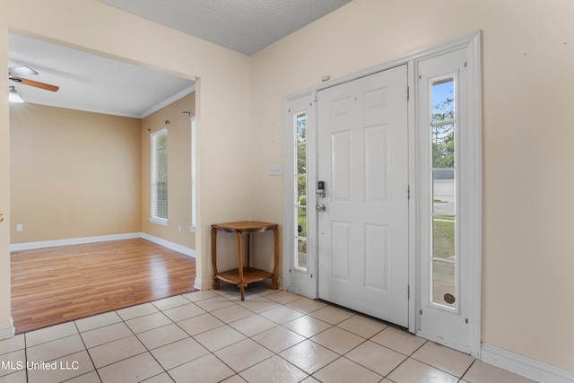 entrance foyer featuring light hardwood / wood-style floors, a textured ceiling, ornamental molding, and plenty of natural light