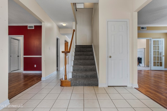 stairway featuring a textured ceiling, ornamental molding, and hardwood / wood-style floors