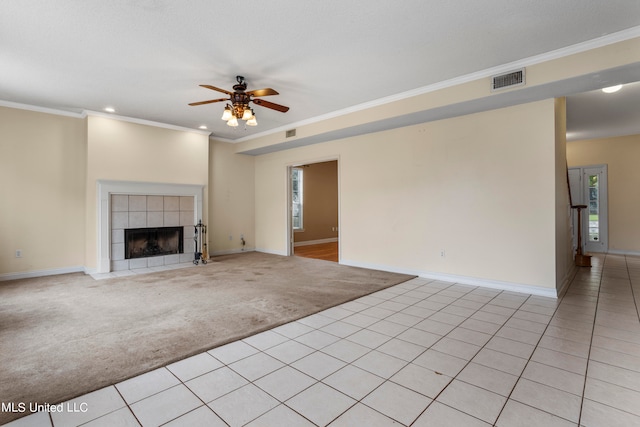 unfurnished living room featuring light carpet, crown molding, a tile fireplace, and ceiling fan