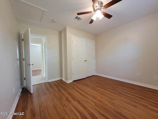 unfurnished bedroom featuring visible vents, ceiling fan, baseboards, wood finished floors, and a closet