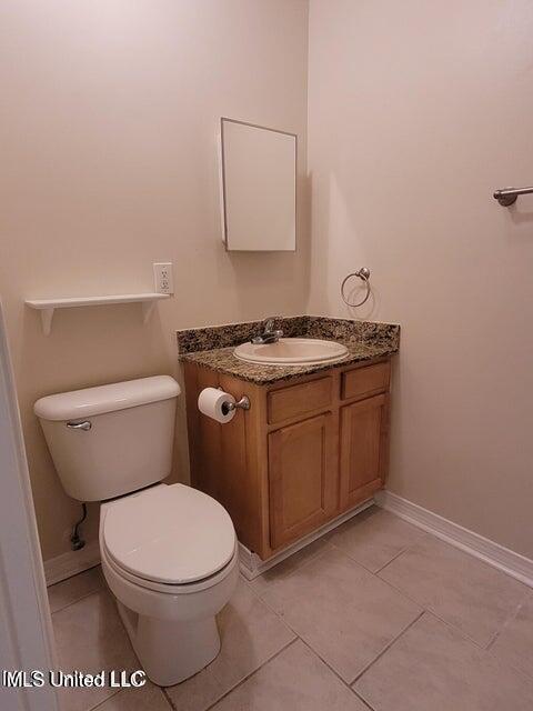 bathroom with tile patterned flooring, toilet, vanity, and baseboards