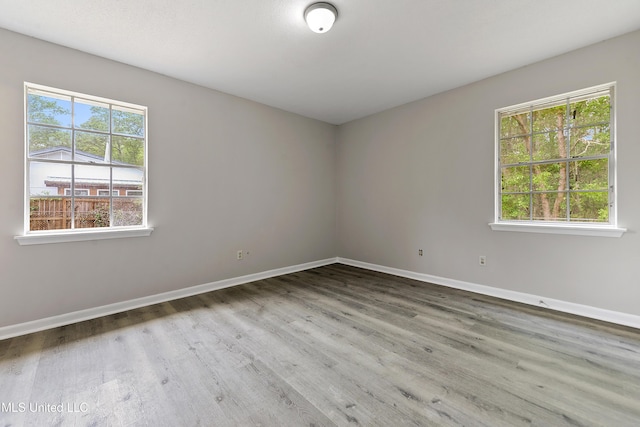 empty room with a wealth of natural light, baseboards, and wood finished floors