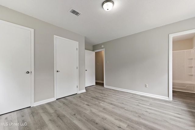 unfurnished bedroom featuring wood finished floors, baseboards, and visible vents