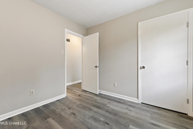 unfurnished bedroom with wood finished floors and baseboards