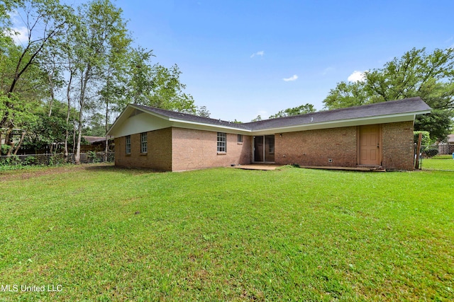 rear view of property with a yard, fence, and brick siding
