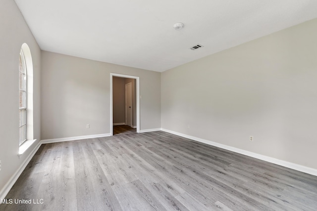 empty room with visible vents, baseboards, and wood finished floors