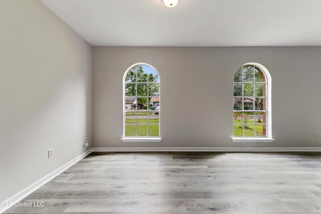 spare room with wood finished floors, baseboards, and plenty of natural light