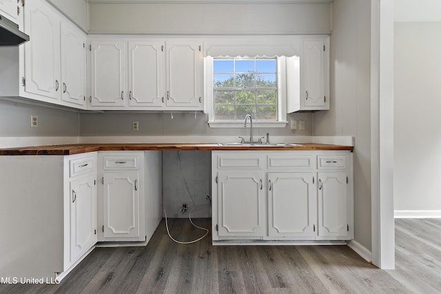 kitchen featuring wooden counters, a sink, white cabinetry, and under cabinet range hood