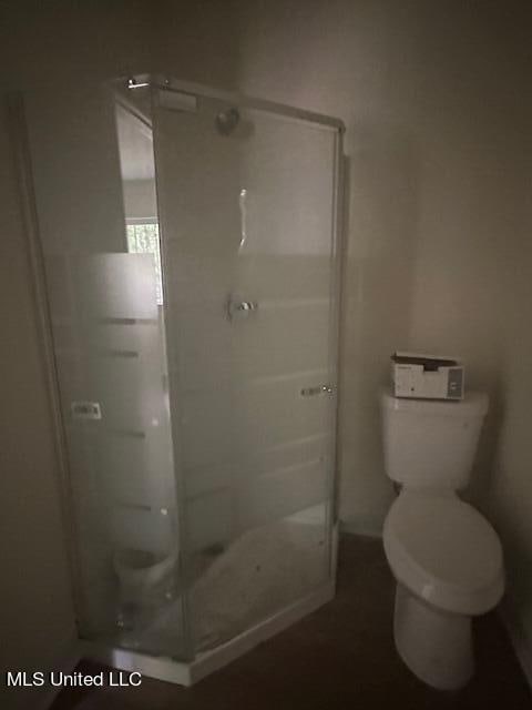 bathroom with toilet and a shower with door