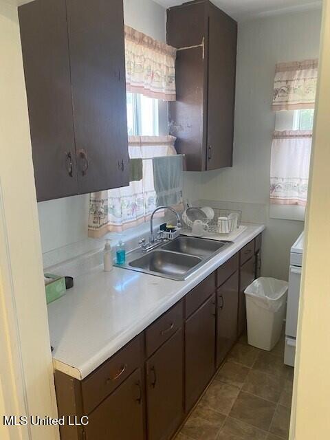 2524 18th Ave, Gulfport, MS 39501 - kitchen featuring light countertops, dark brown cabinets, a sink, and dark tile patterned flooring