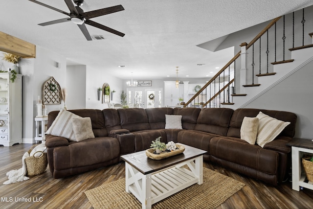 living area with visible vents, dark wood-type flooring, ceiling fan with notable chandelier, a textured ceiling, and stairway