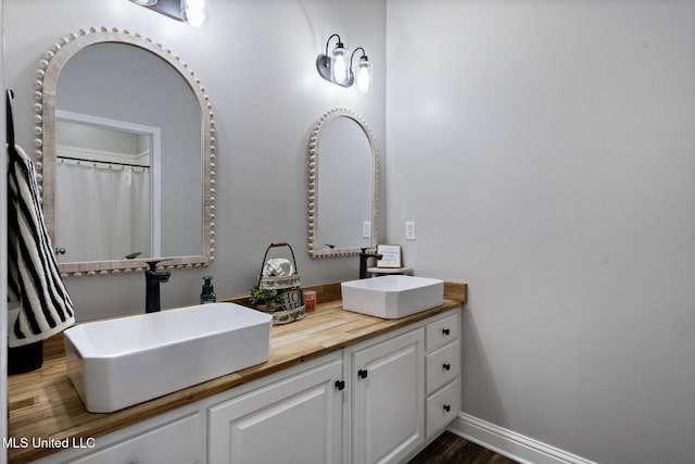 bathroom featuring double vanity, baseboards, and a sink