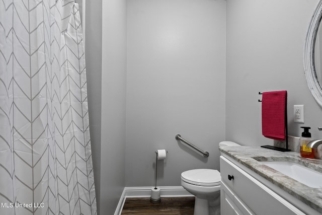 bathroom with vanity, wood finished floors, baseboards, curtained shower, and toilet