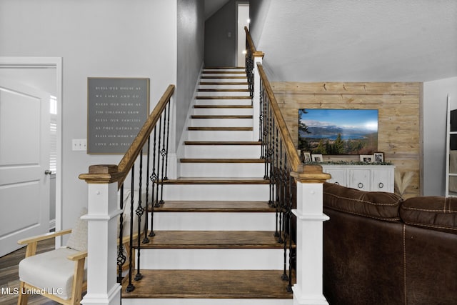 stairway with wooden walls and a textured ceiling