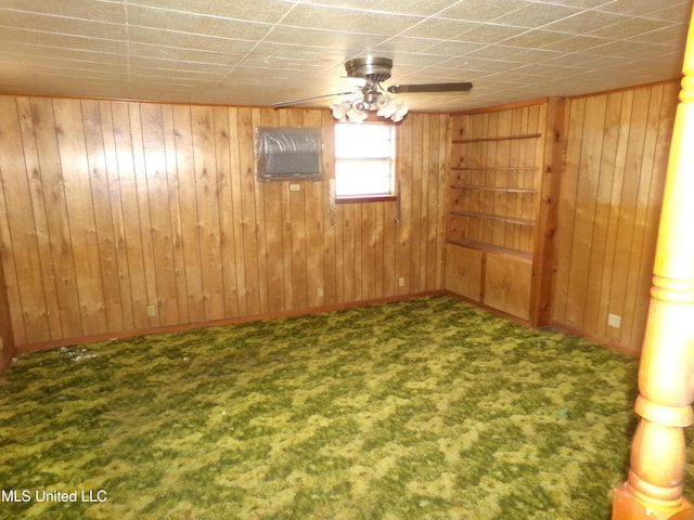 carpeted spare room with wood walls and ceiling fan