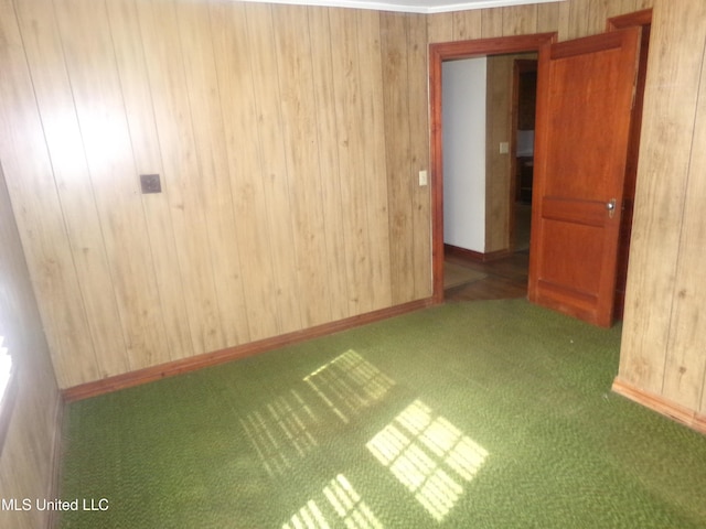 carpeted empty room featuring wooden walls and baseboards