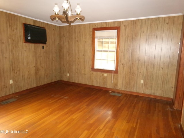 empty room featuring ornamental molding, baseboards, an inviting chandelier, and wood finished floors