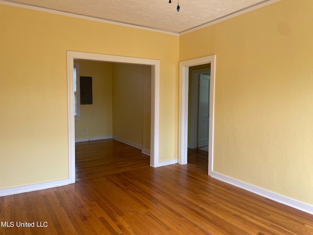 spare room featuring electric panel, crown molding, a textured ceiling, and hardwood / wood-style flooring