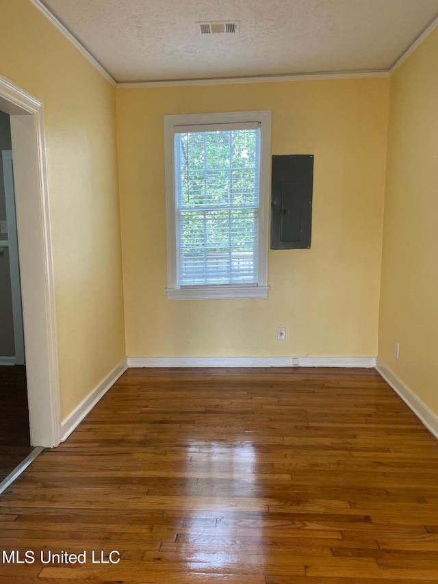 unfurnished room with wood-type flooring, electric panel, ornamental molding, and a textured ceiling