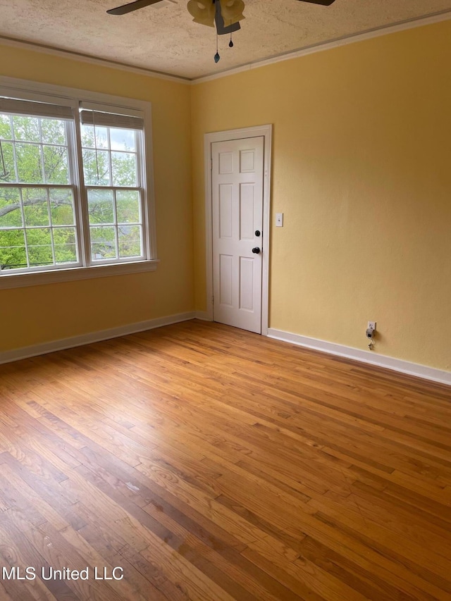 empty room featuring a textured ceiling, ornamental molding, and light hardwood / wood-style flooring